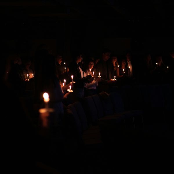 people holding candles in the dark during a vigil.