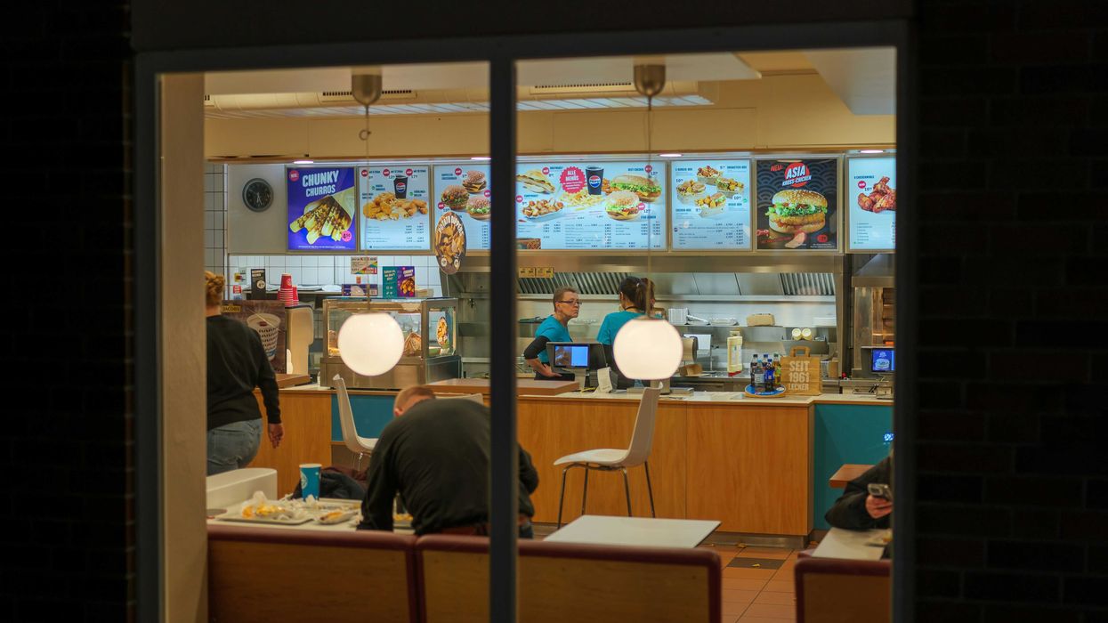 People inside a brightly lit fast food restaurant at night.