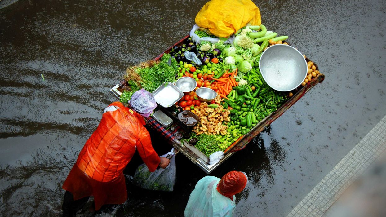 People pushing a vegetable cart through flooded streets.