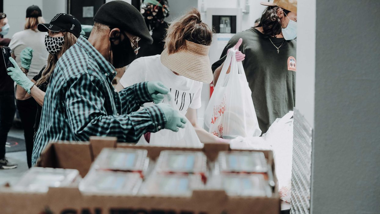 people standing in front of brown cardboard boxes of strawberries.