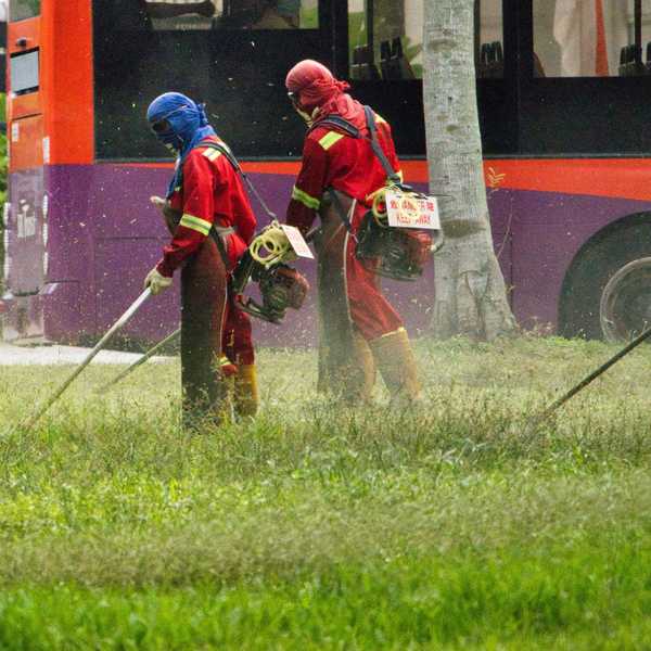 People wearing colorful protective gear and masks spray pesticides in a park.