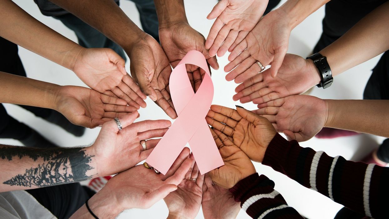 peoples hands holding a pink ribbon