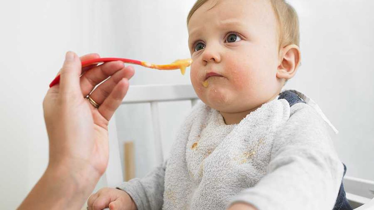 Person feeding a small child sitting in a high chair