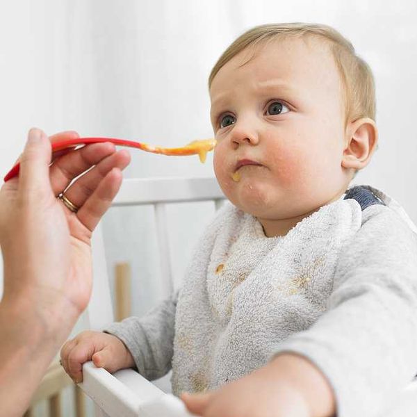 Person feeding a small child sitting in a high chair