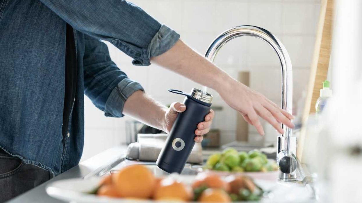 person filling hydration bottle with tap water