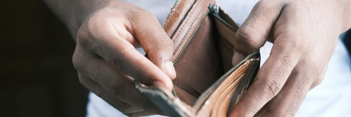 person holding empty brown leather bifold wallet.