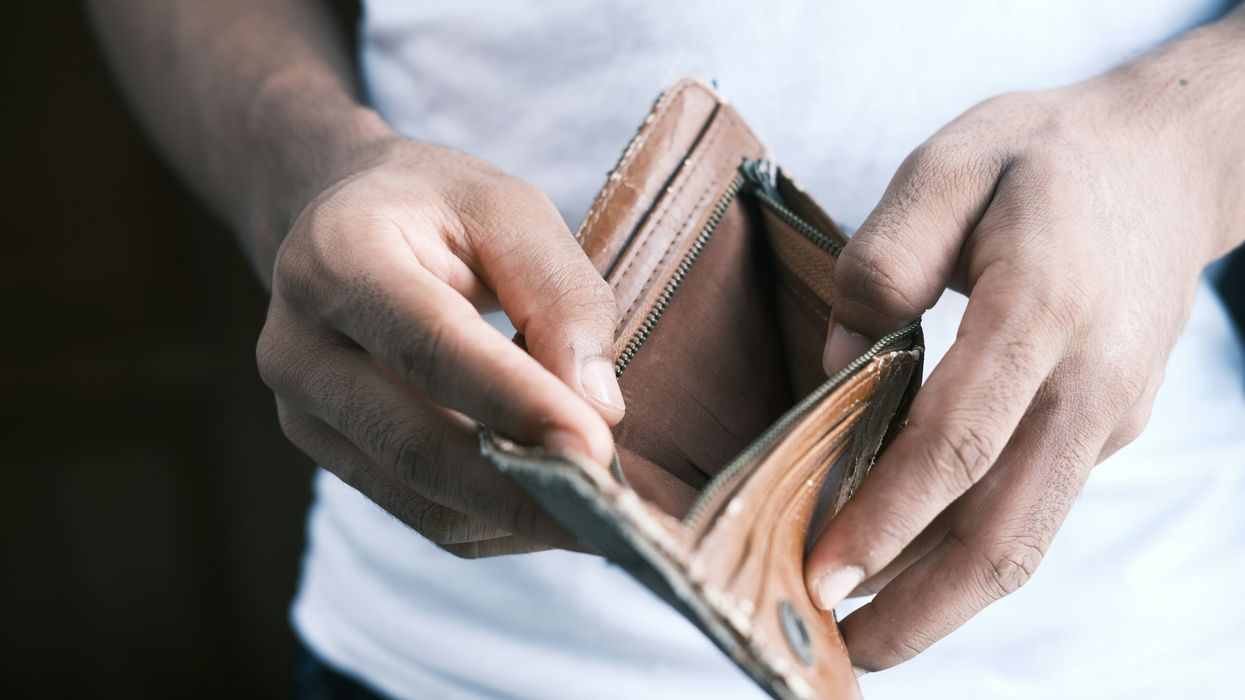 person holding empty brown leather bifold wallet.