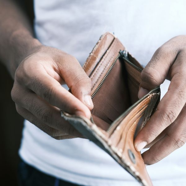 person holding empty brown leather bifold wallet.