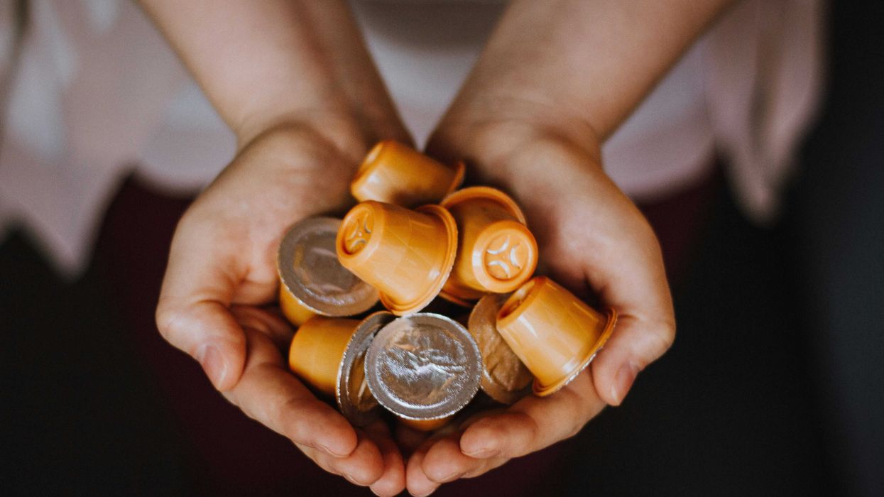 person holding plastic coffee pods in palms.