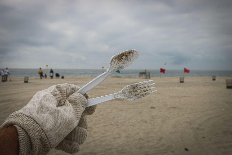 person holding white plastic disposable fork and spoon.