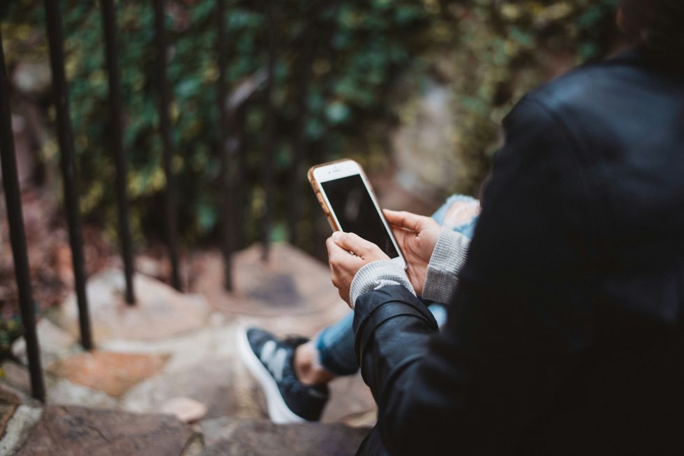 person holding white smartphone while sitting.