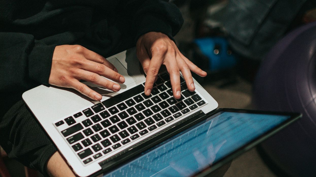person in black pants and white socks using macbook pro.