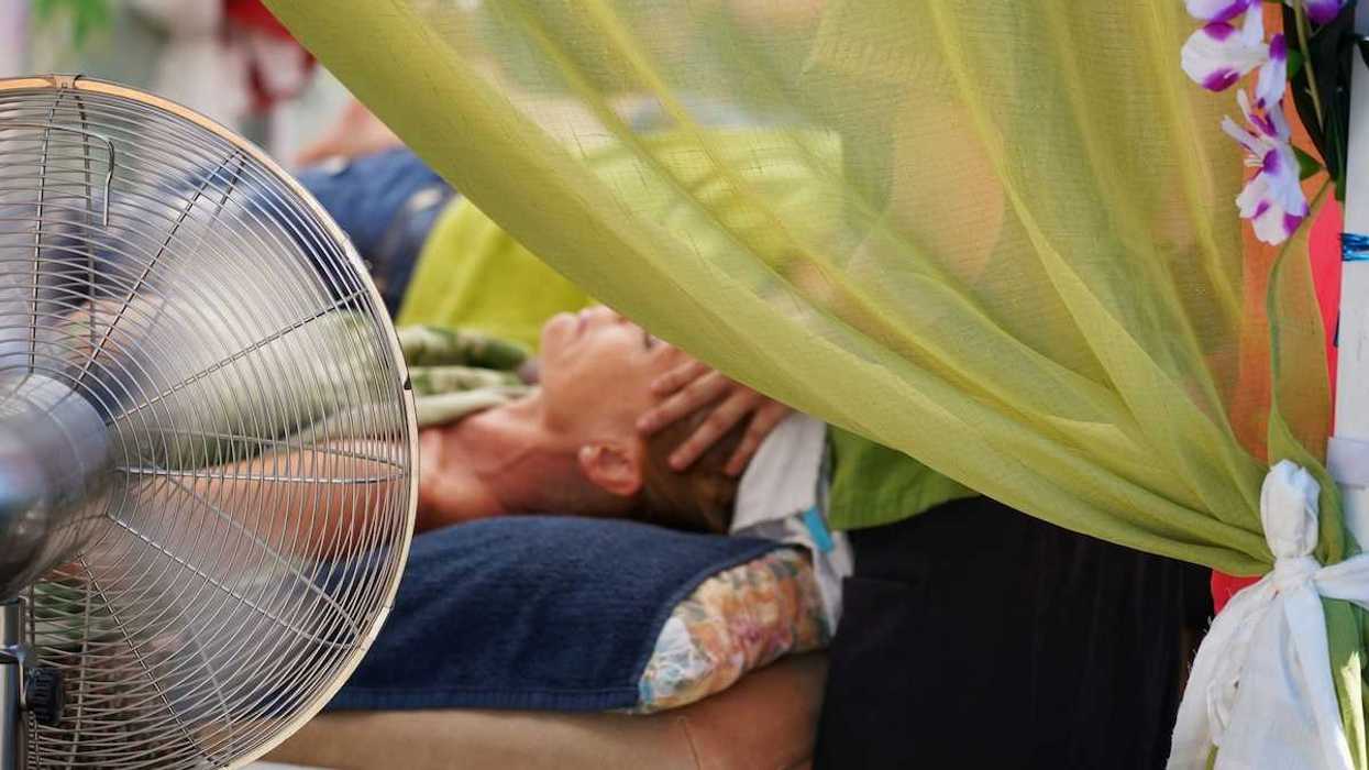 person in supine position receiving massage therapy in front of portable fan