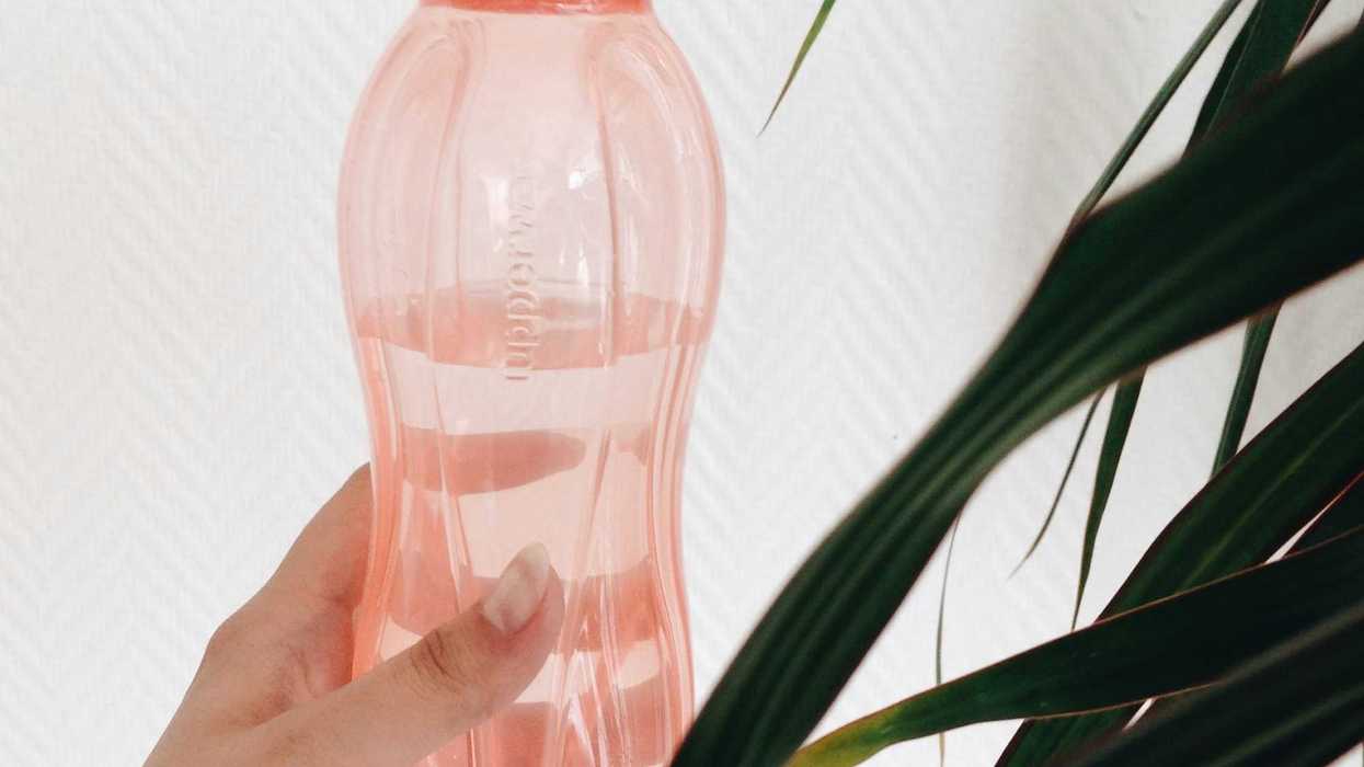 person's hand holding pink plastic water bottle.