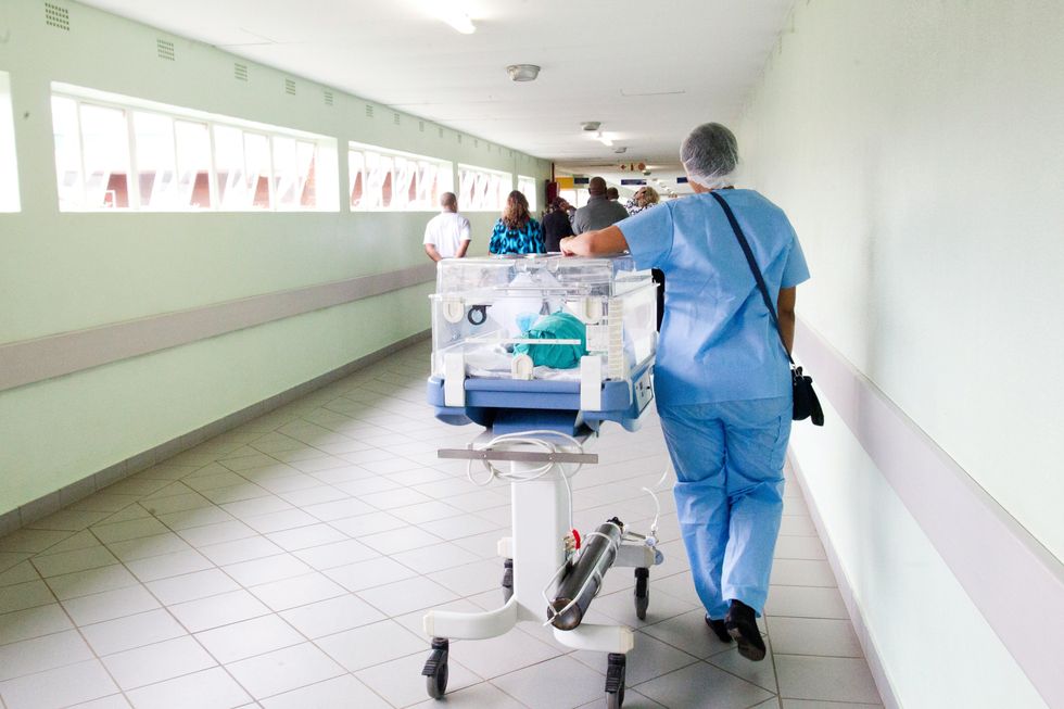 person walking in hospital in blue scrub suit near incubator