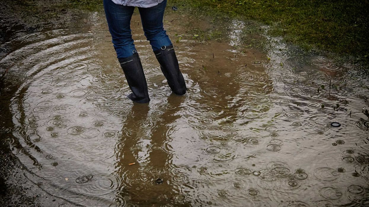 person with rain boots standing in floodwaters.