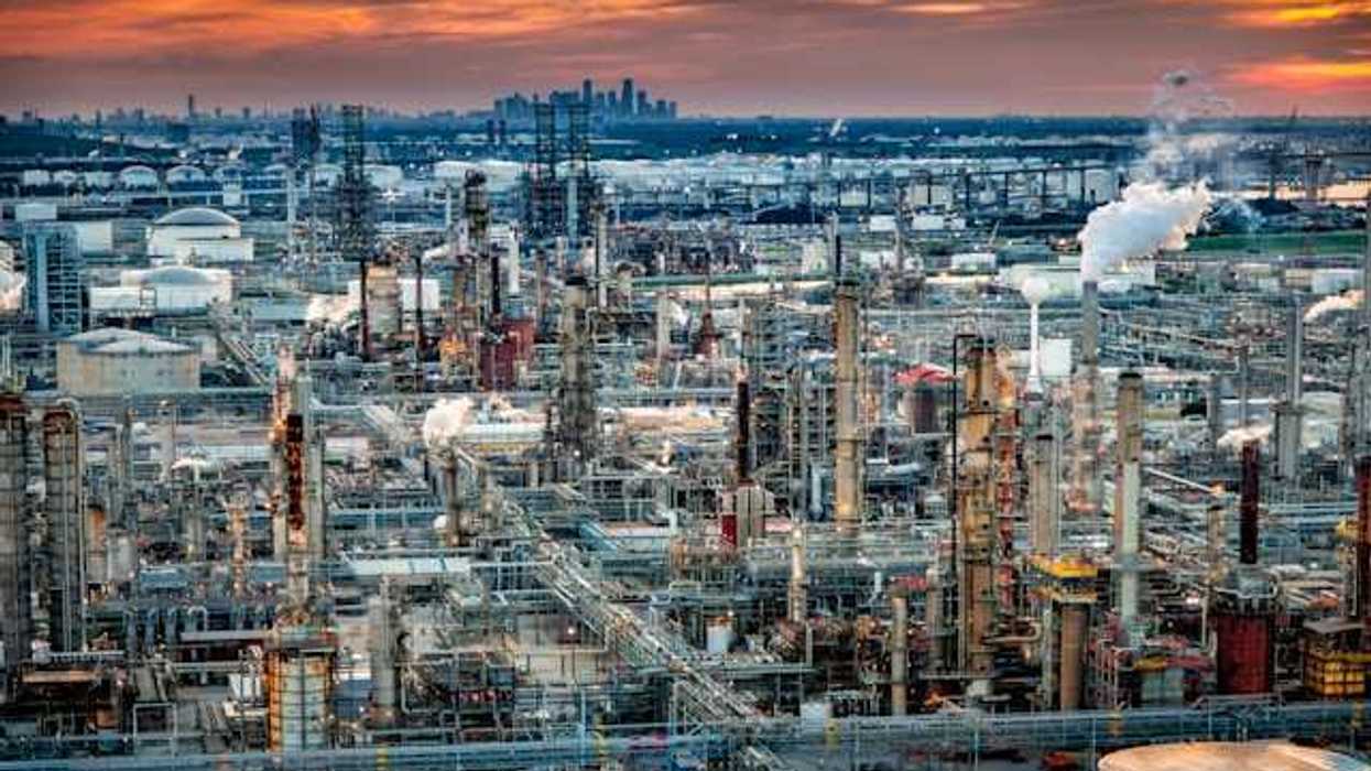 Petrochemical plant at sunset with city skyline in the background