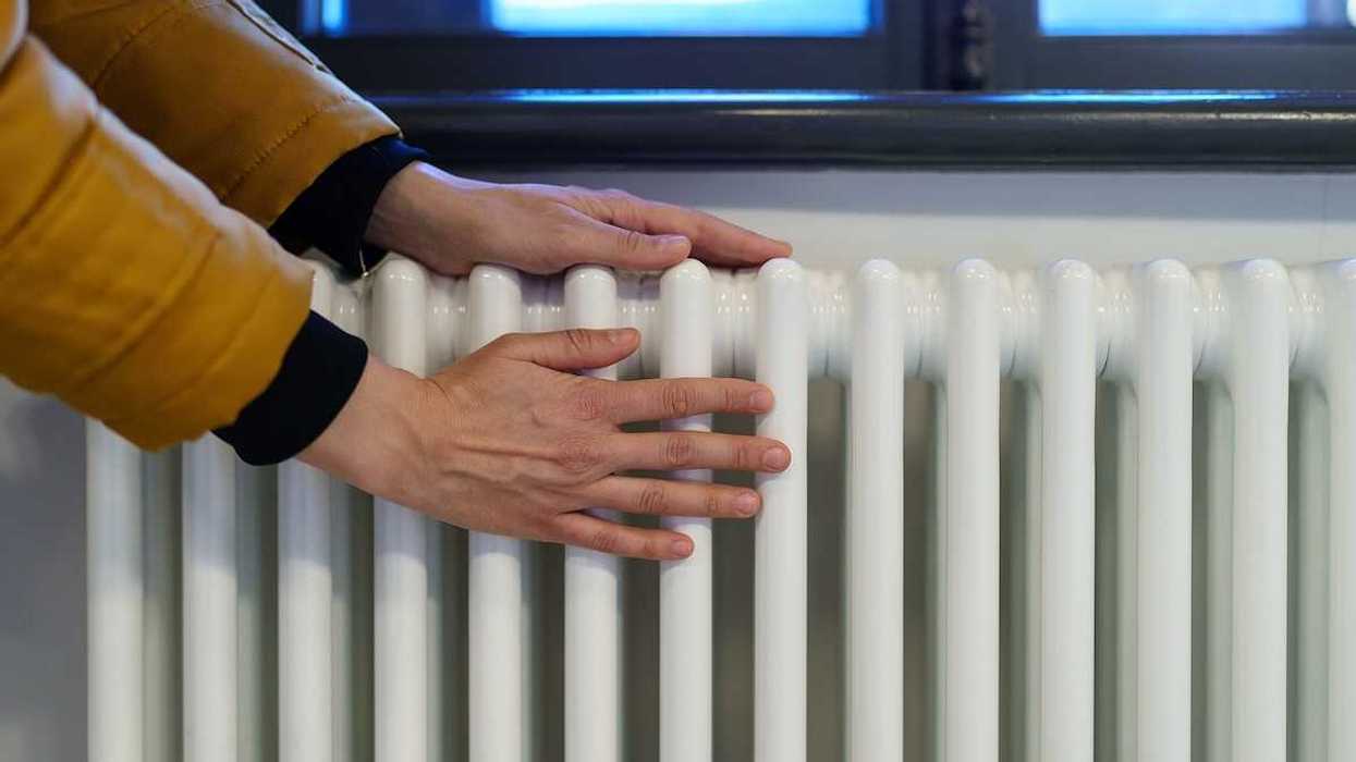 Photo of hands being warmed on an old-fashioned style radiator.