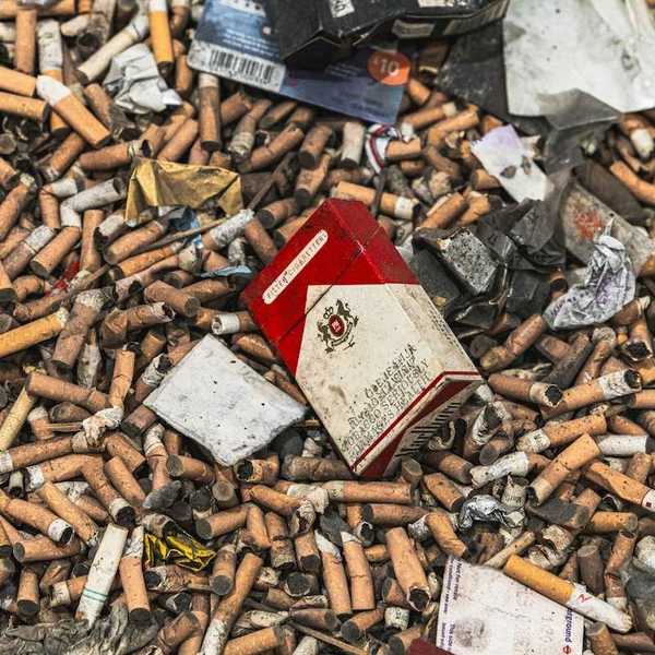 Pile of cigarette butts interspersed with other cigarette smoking waste