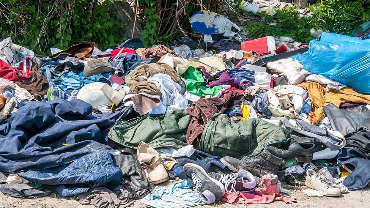 Pile of old clothing and trash on the side of a road