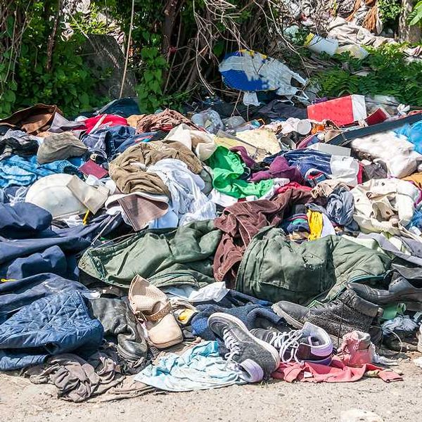 Pile of old clothing and trash on the side of a road