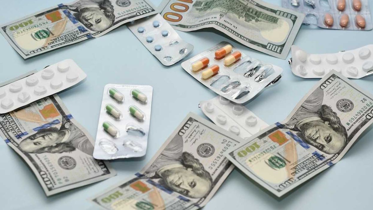 Pills interspersed with hundred-dollar bills scattered on a table