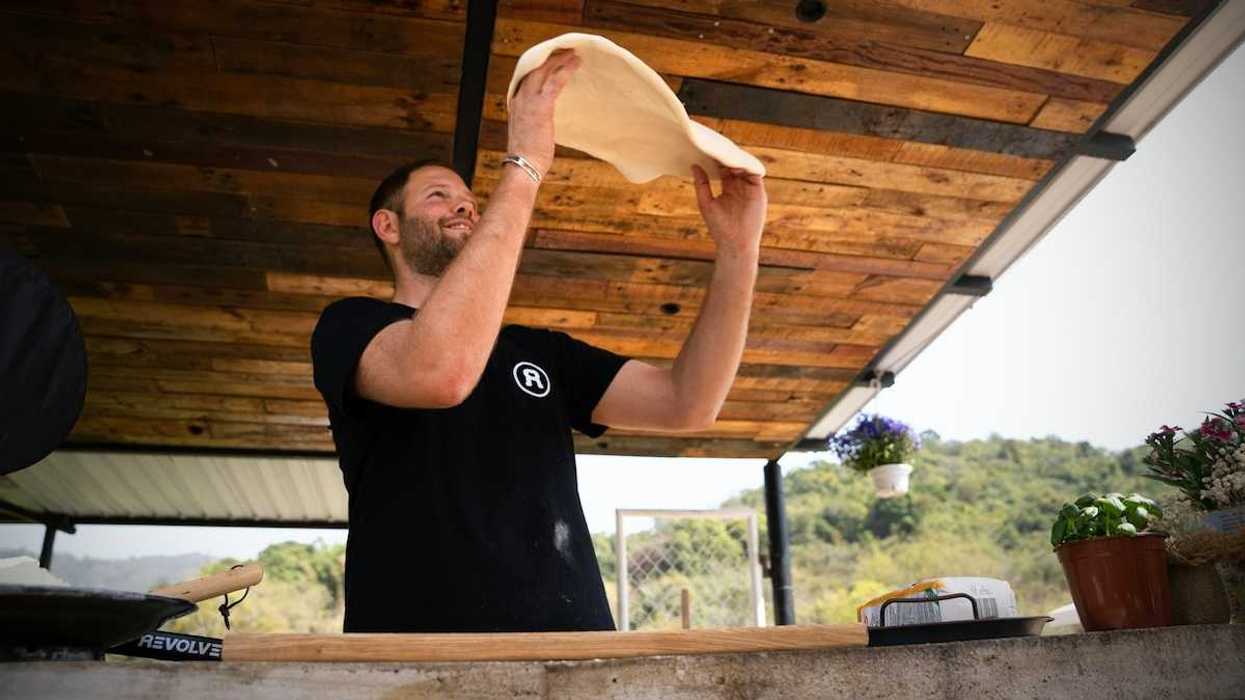 Pizza maker in black tee-shirt throwing dough at outdoor venue