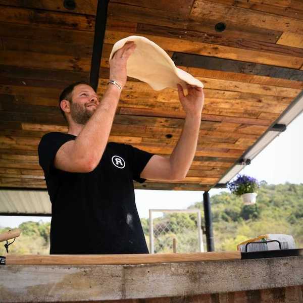Pizza maker in black tee-shirt throwing dough at outdoor venue