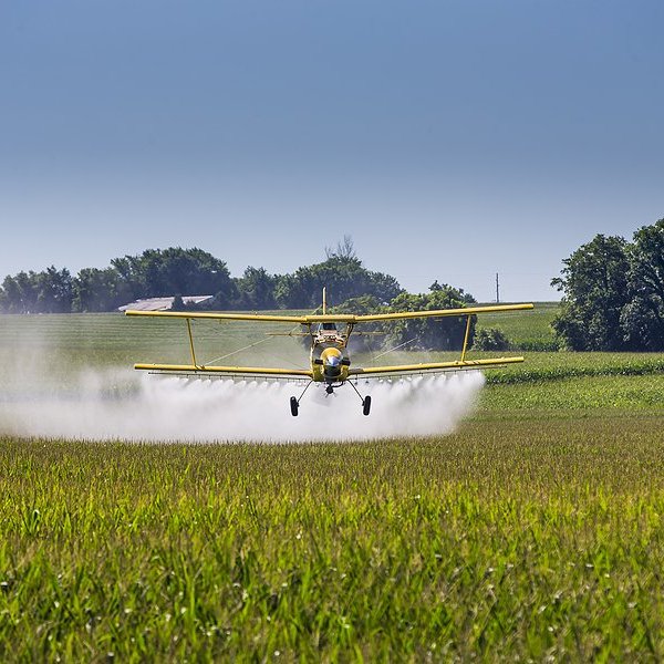 plane spraying pesticides over a field