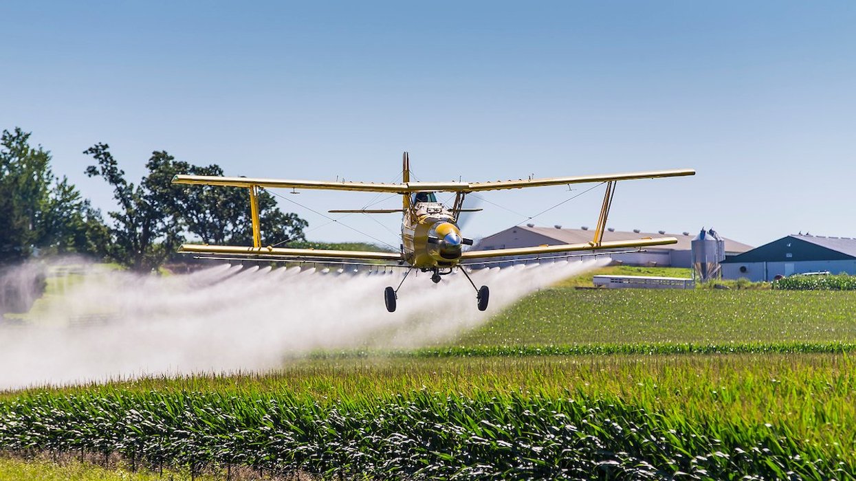 plane spreading pesticides on a field