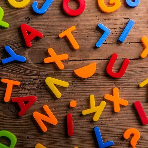Plastic letters randomly scattered onto a wooden background