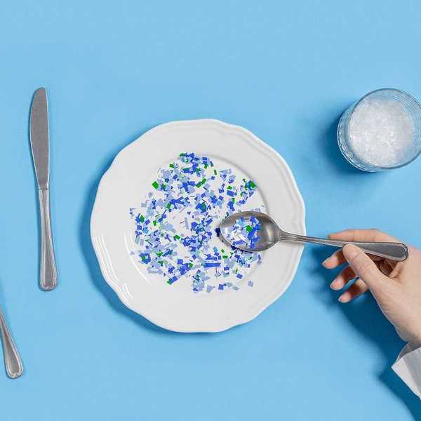 Plate with plastic pieces instead of food and glass of microplastics instead of water.
