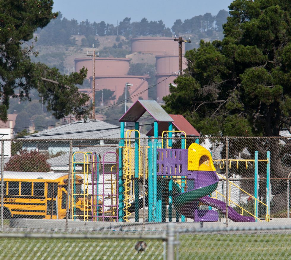 Playground in foreground of oil refinery
