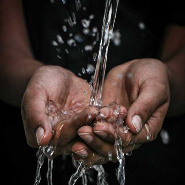 pouring water on person's hands.