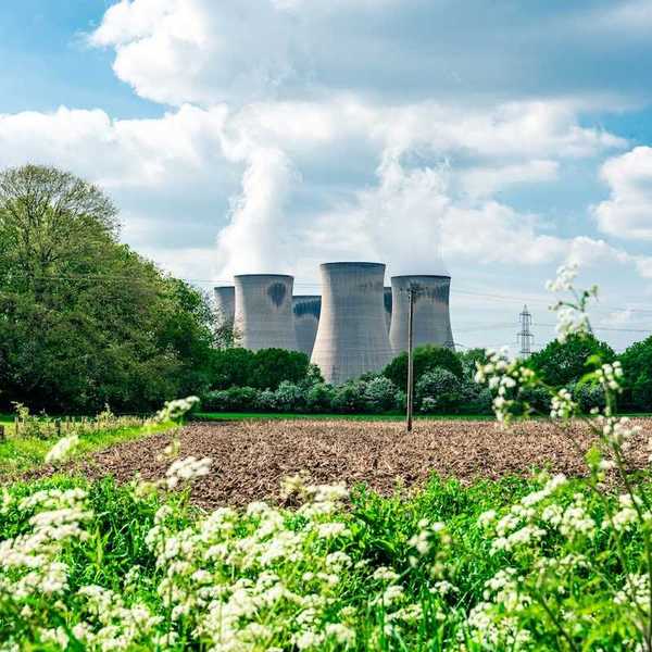 Power plant adjacent to plowed field and wildflowers