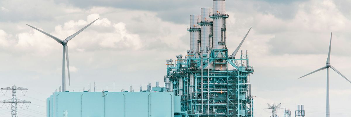 Power plant with wind turbine in the background.