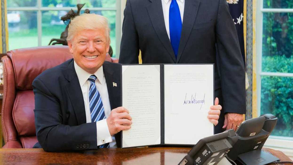 President Trump smiling while displaying a recently signed executive order