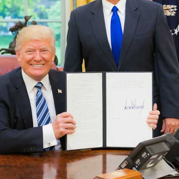 President Trump smiling while displaying a recently signed executive order