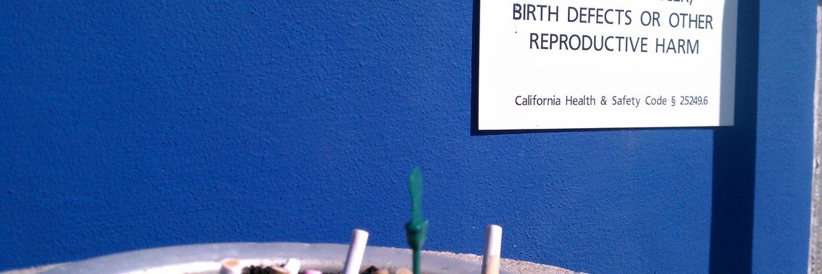 Prop 65 warning label near an ash tray full of cigarette butts