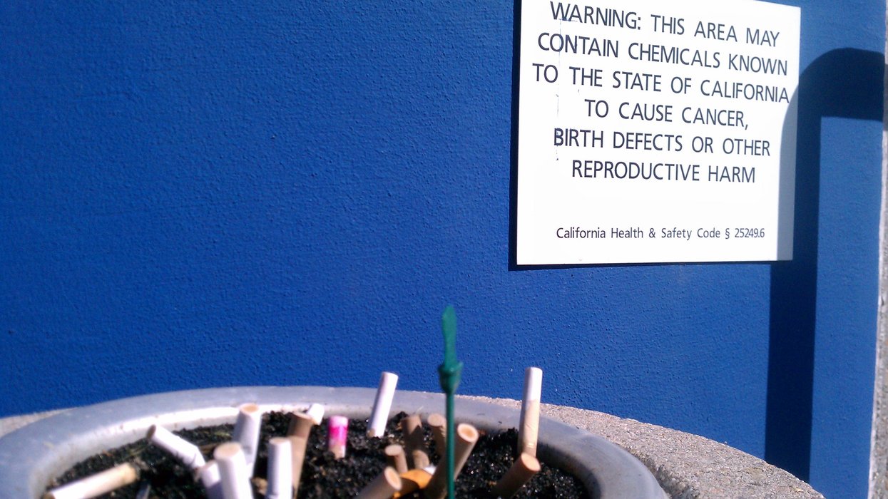 Prop 65 warning label near an ash tray full of cigarette butts