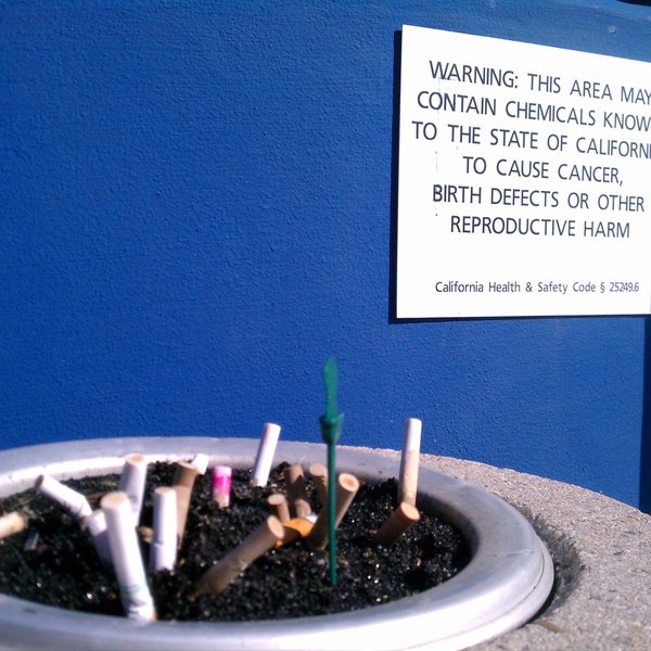 Prop 65 warning label near an ash tray full of cigarette butts
