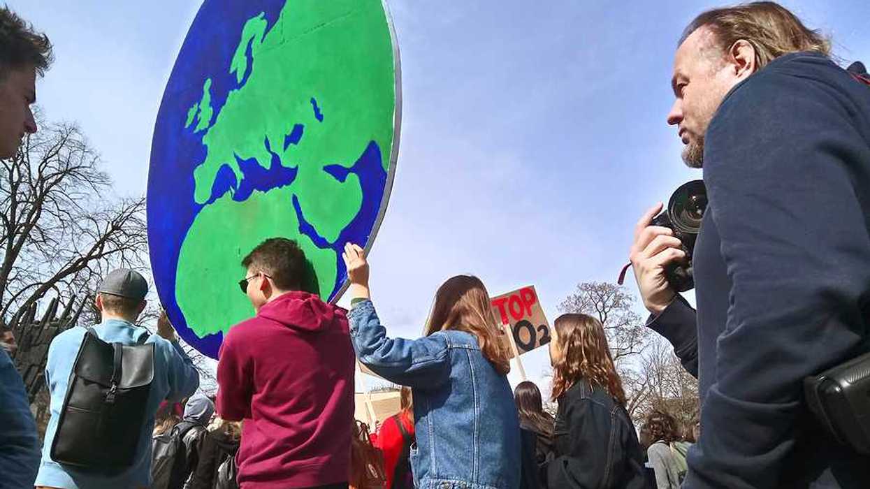 Protesters carrying a large sign in the shape of the Earth