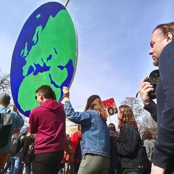 Protesters carrying a large sign in the shape of the Earth