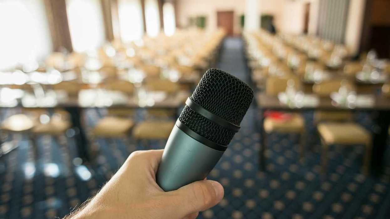Public hearing space with microphone in foreground and empty seats in a blurry background