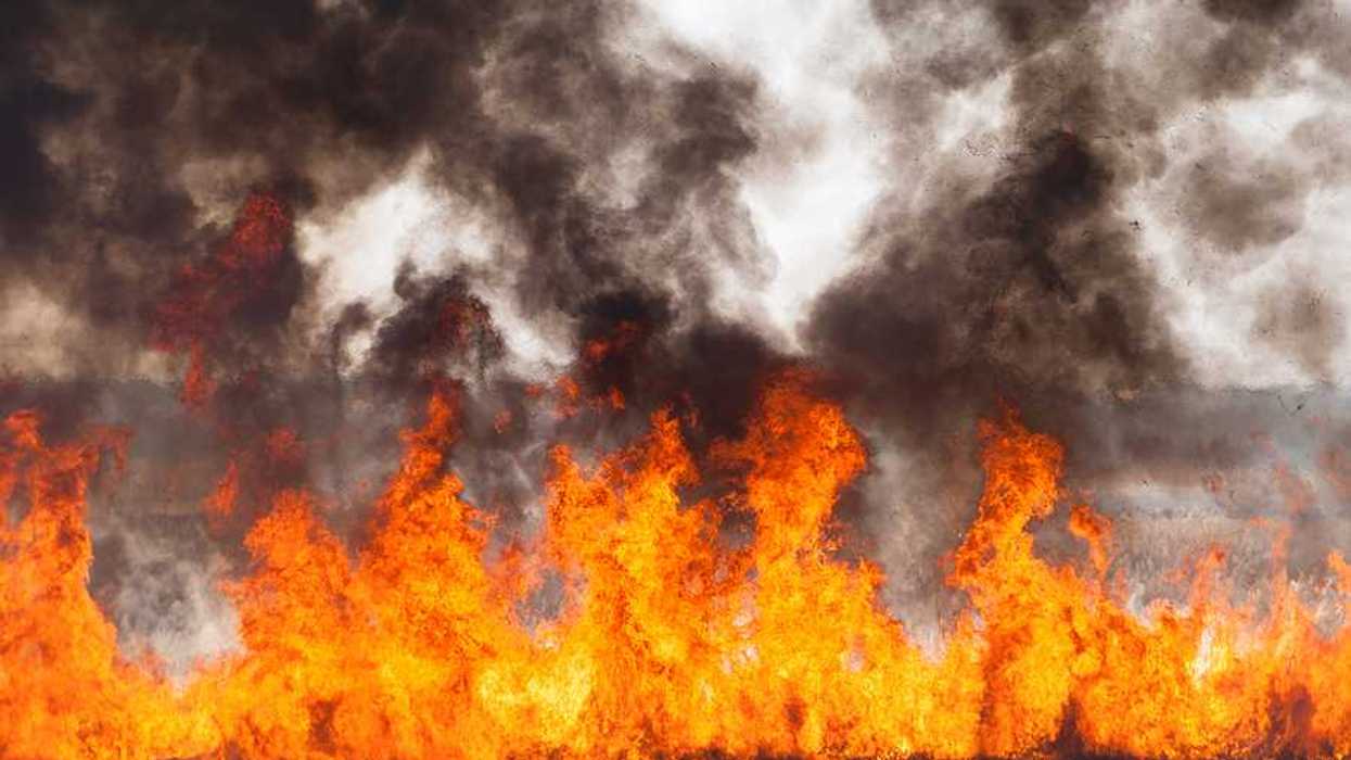 Red and orange flames with black smoke in the distance