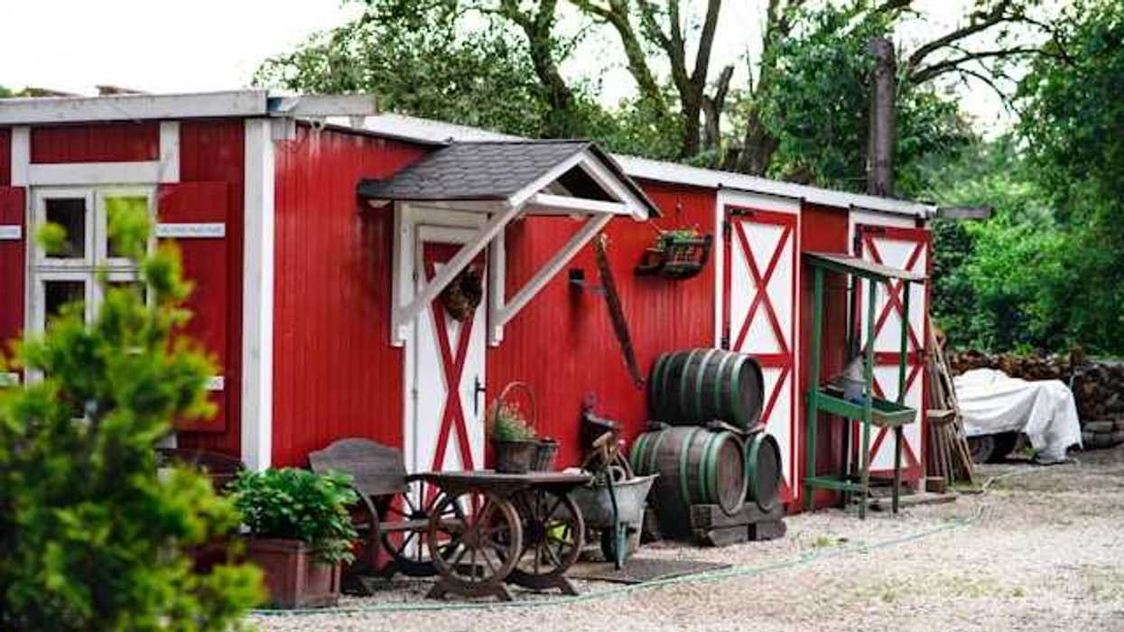 Red and white barn buildings with trees in the background