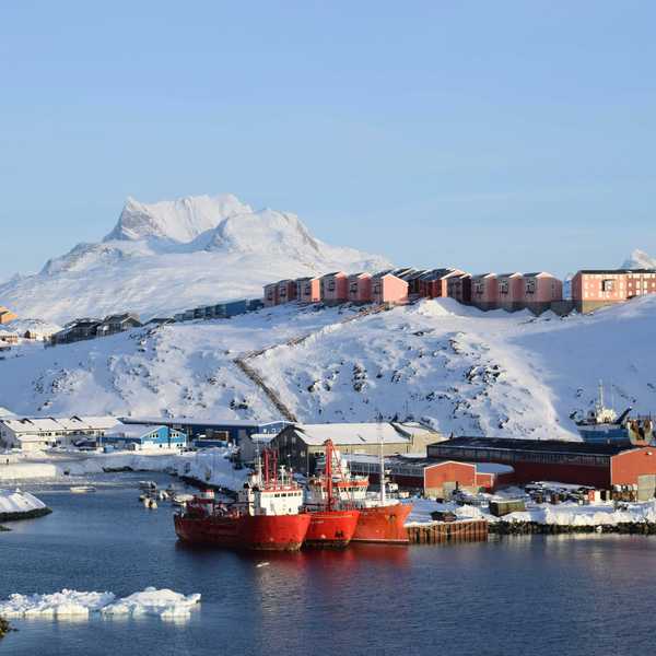 red and white ship on sea near snow covered mountain during daytime