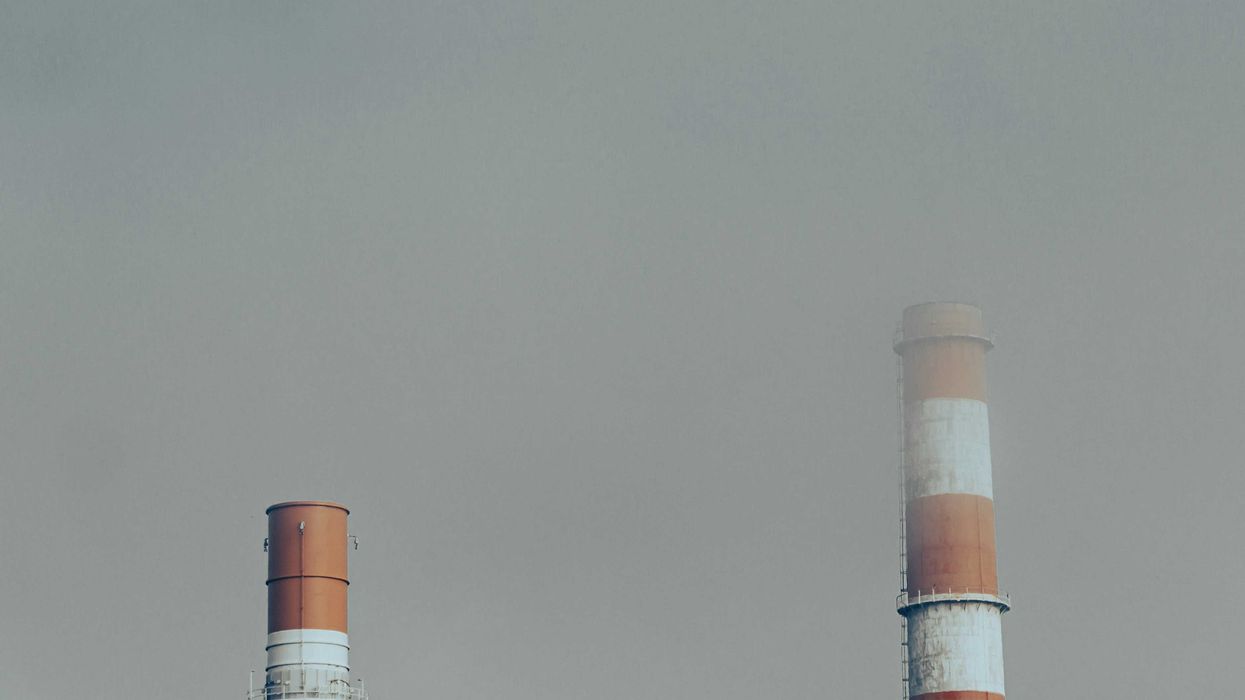 Red and white smokestacks surrounded by a smoky sky