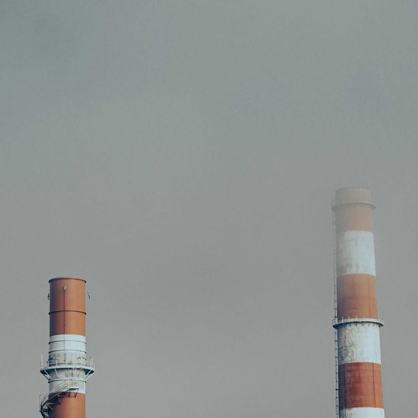 Red and white smokestacks surrounded by a smoky sky