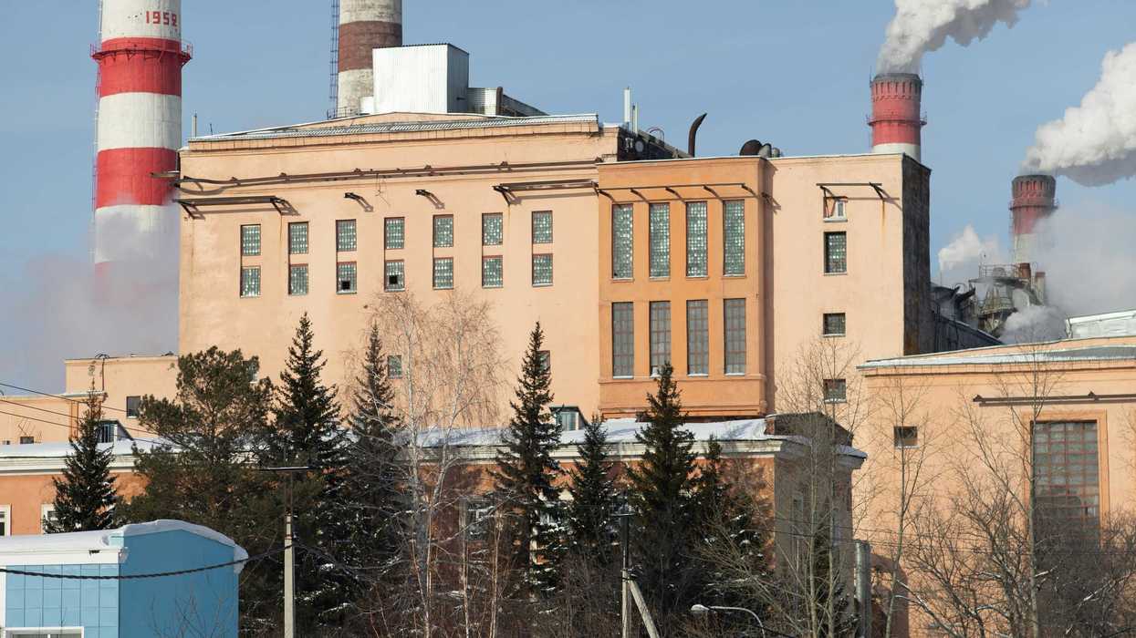 Red and white striped power plant smokestacks with billowing smoke emitting from the top